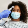Doctor examining black patient wearing protective face mask in hospital