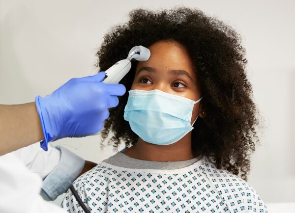 Doctor examining black patient wearing protective face mask in hospital